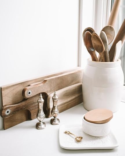 white background with cutting board, salt cellar, and wooden spoons in a white container
