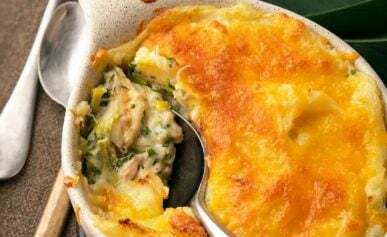 Fish pie with leeks being spooned out of a casserole.