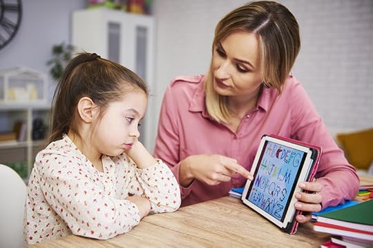 photo of a mother helping her bored young daughter look at the alphabet on an ipad screen. When children don't reach speech language milestones early in life, it may indicate early signs of reading difficulties.