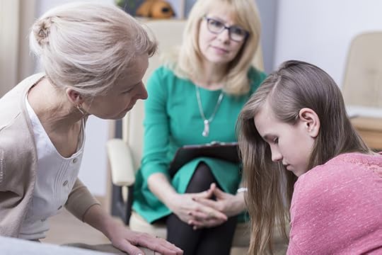 A mother and teenage daughter speak with a school counselor or teacher. Everyone looks sad and concerned.