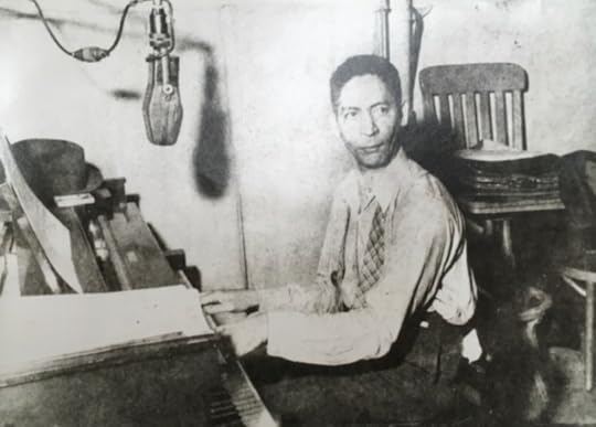Jelly Roll Morton, seated at piano, a microphone in front of him