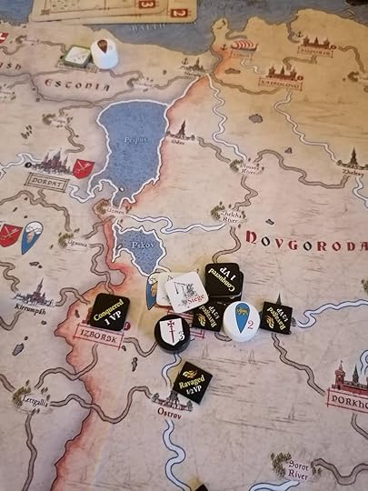 Gavrilo's lord cylinder next to the city of Pskov with two Rus siege markers. A Teutonic lord's cylinder is also next to them. In the background Valdemar's cylinder is next to a Rus Conquered token on a Teutonic city.