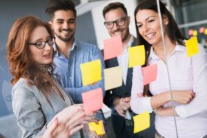 Team standing around a wall covered in post-it notes