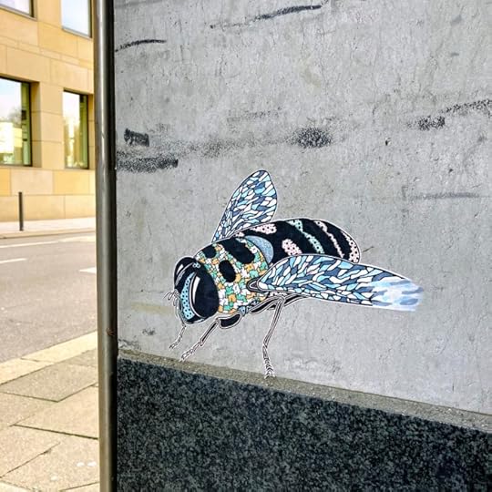 Papierklebekunst an einer Hauswand, eine bunte Fliege