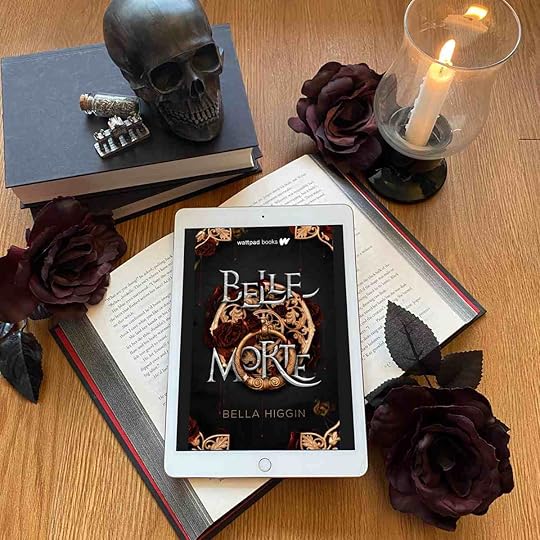Belle Morte book on a red book, wiht dark red roses, a black skull, and a lit candle