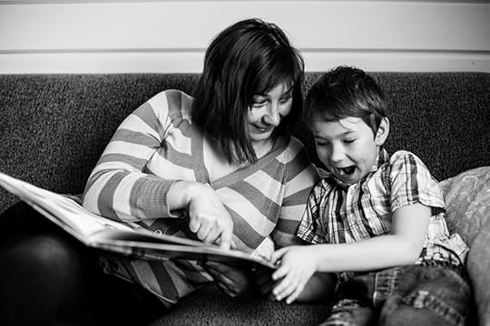 black and white photo of a boy and his mother reading together from a large picture book while sitting on a couch. The boy looks very excited. Dyslexia is like black-and-white photography in a way. Sometimes a limitation imposed on a creative process can produce beautiful results.