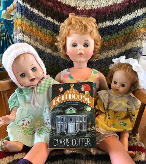 Dolls posed with a copy of The Dollhouse by Charis Cotter