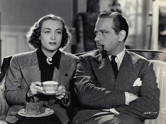 A young Joan Crawford (1938) drinking coffee from a teacup. She is wearing a spiral diamond brooch at her throat.