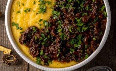 A bowl of polenta with mushroom ragu, with dried mushrooms alongside.
