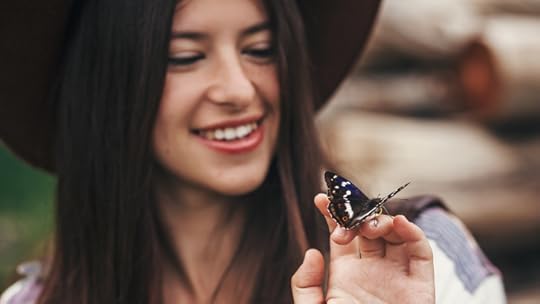 young woman in a hat holding a black butterfly on her fingers