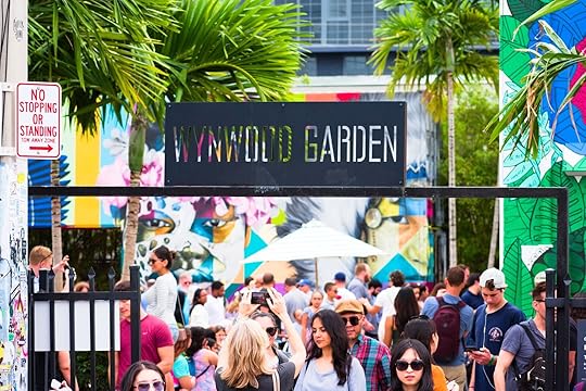 Wide view of crowd of people walking in Wynwood Garden at colorful contemporary Wynwood Walls outdoor art district graffiti mural painting museum