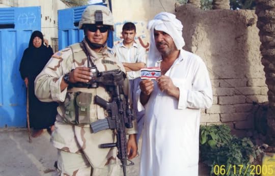 Color image of a U.S. soldier in full battle gear, wearing sunglasses, smiling, standing among three Afghans citizens