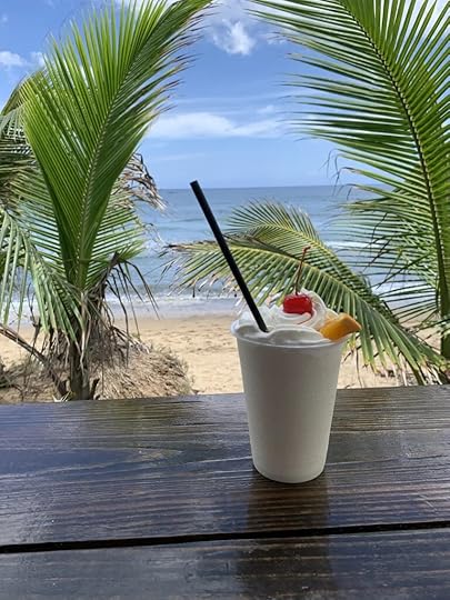 A piña colada against a backdrop of beach, sun, and sky