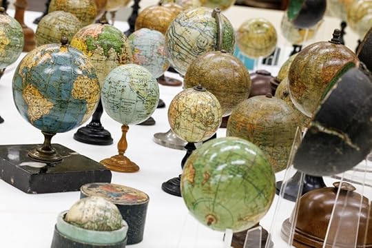 Dozens of tiny globes stand on a table.