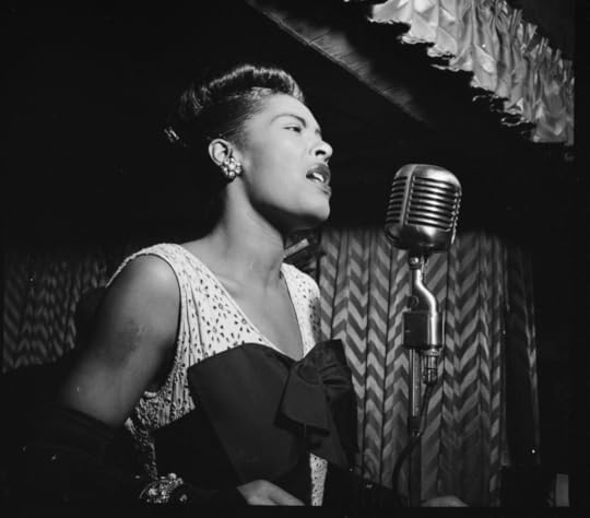 Billie Holiday onstage, singing into a microphone.