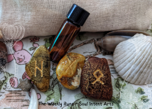 Elder runes Othala, Gebo, and hagalaz in Baltic amber, with a brown vial and fossilized crinoid on a Winnie the Pooh fabric