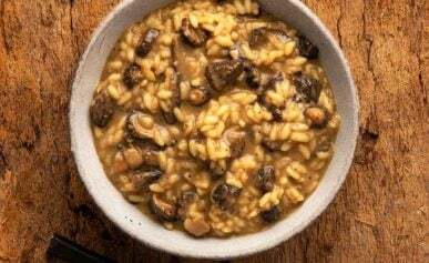 A bowl of mushroom risotto on a wooden table.