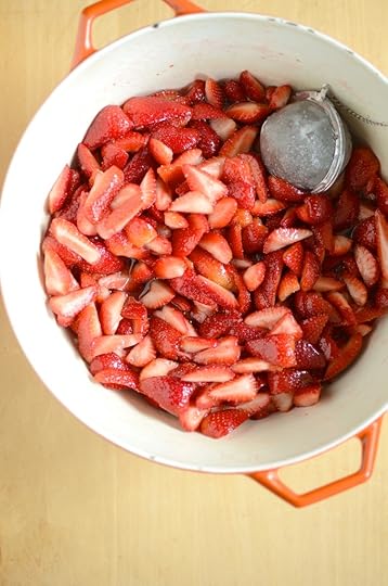 Chopped and sugared strawberries in an enamel pot with a tea ball.