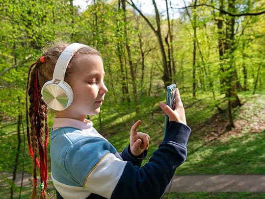 A girl outdoors wearing headphones listens to an audiobook as she takes a walk. Audiobooks, dyslexia, and the brain have a