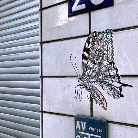 Klebkunst: Ein papierner Schmetterling an einer gekachelten Wand