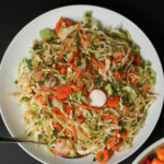 overhead shot of mexican coleslaw in large white bowl with serving spoon.