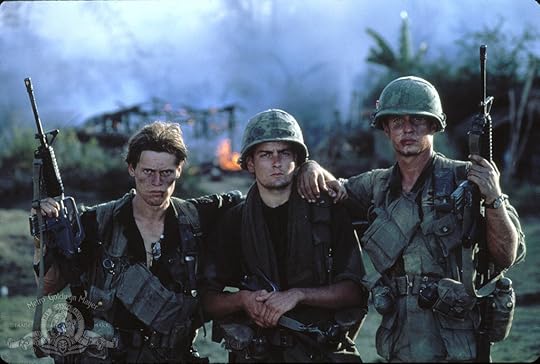 Three American soldiers in a Vietnam jungle setting staring at the camera.