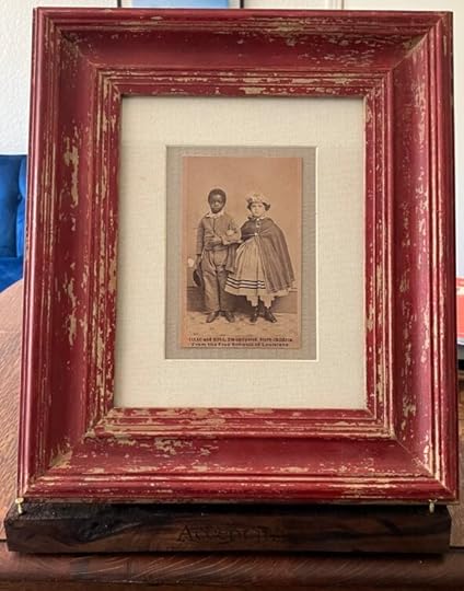Photo of multimedia piece with archival photo of two children who were emancipated slaves, wood burned shelf with text and frame.