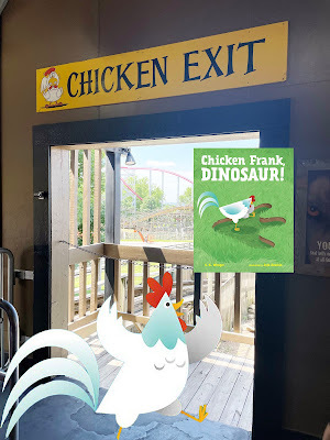 An illustrated chicken stands in front of a real life doorway with a rollercoaster in the background. Over the door is a sign that says