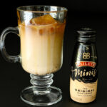 glass of iced coffee next to mini bottle of baileys.