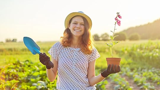 teenage girl in field holding a plant and trowel