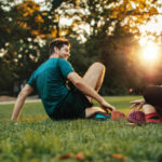 A happy athletic couple sit in the grass to stretch