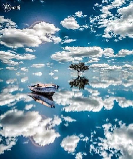 An empty rowing boat lying on a still lake with a leafy green tree behind it, and a blue sky with fluffy clouds perfectly reflected in the water so the horizon is invisible. Created by Barath Ganesh
