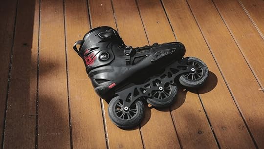 Black rollerblade against a brown hardwood floor