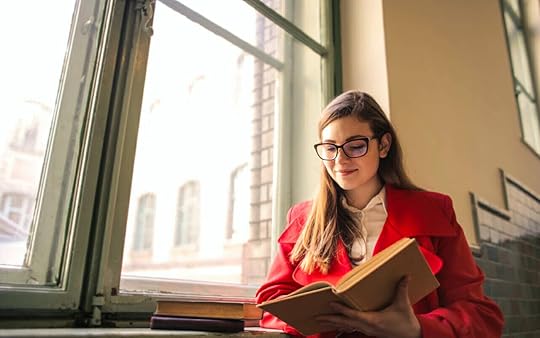red coat woman is reading beside a window