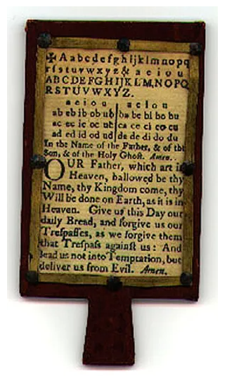 The photo shows an early children's book, a Horn book. It is a wooden paddle with a piece of parchment glued to it. On the paper is the alphabet and the Lord's prayer. The parchment is covered by a thin sheet of see through horn to protect the paper from damage.
