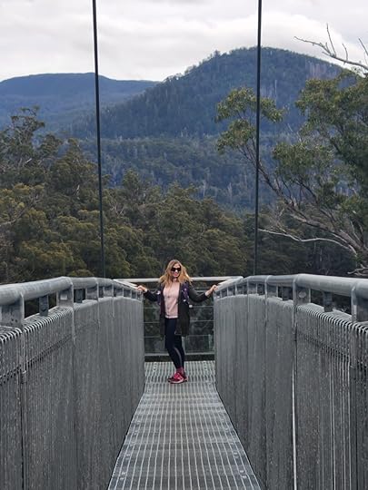 A woman with blonde hair standing on a bridge overlooking Tasmanian wilderness
