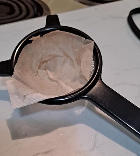 Makeshift coffee filter with used coffee bag in mesh strainer