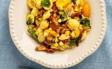 A plate of chanterelle pasta with cherry tomatoes, sweet corn, basil and golden bell pepper.