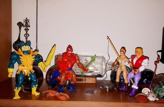 Mer-Man and Clawful attack Adam and Teela on the beach.