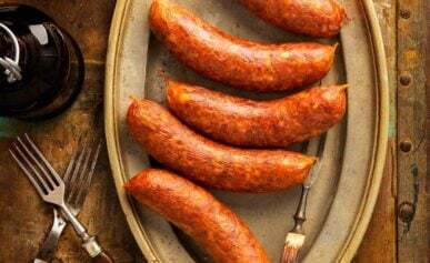 A platter of Texas hot links sausage on a table, with sliced links and potatoes.