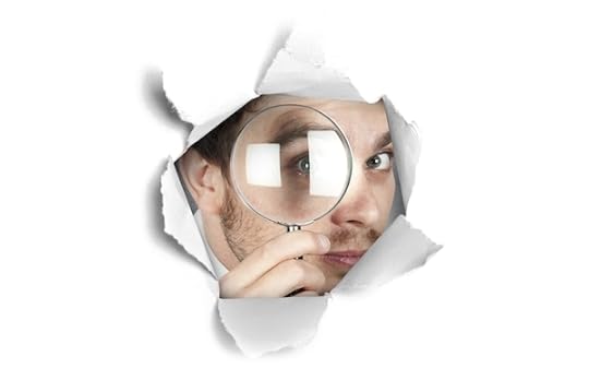 Man using magnifying glass to look through a hole in some paper