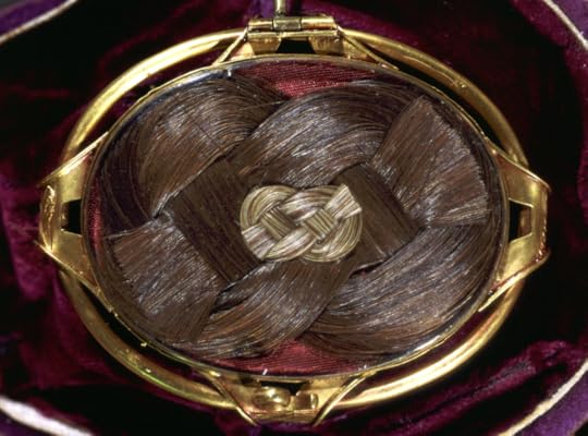 A weaved locket of chestnut brown hair in a gold clasp.