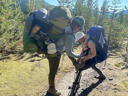 hiker helping hiker tie shoes