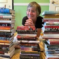 Woman grimacing behind a stack of books.