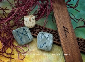 Elder Futhark runes Ansuz (carved into cedar), and Perthro and Mannaz (carved into silver clay) with a beige ceramic owl nested into caloglossa red moss on a tie-dyed yellow, orange, and green background