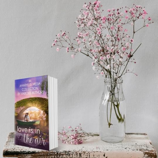 Table with flowers and a book with the cover of Love is in the Air, a charity anthology