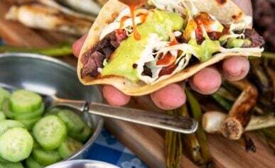 Pouring salsa on tacos al carbon.