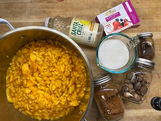 Ingredients for sugar free peach jam. Mashed peaches and apple juice in a pot, bottled lemon juice, cinnamon, nutmeg, cloves, a box of pectin, and a measuring cup with Swerve alternative sweetener.