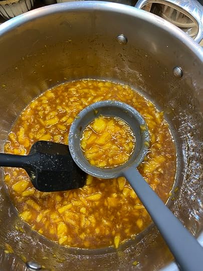 Stainless steel Dutch oven with sugar free peach jam, a grey ladle, and a black spatula inside.