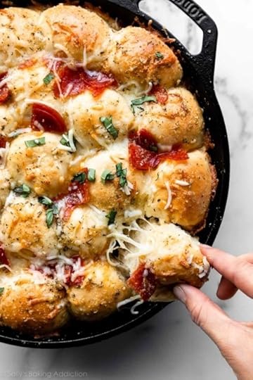 pulling a cheese pepperoni pizza roll out of cast iron skillet.